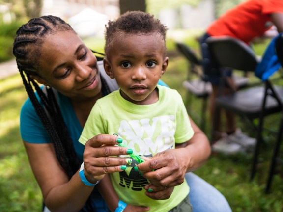 woman hugging child and blowing bubbles