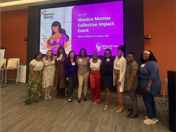 Staff smiling and standing in line in front of large event slide