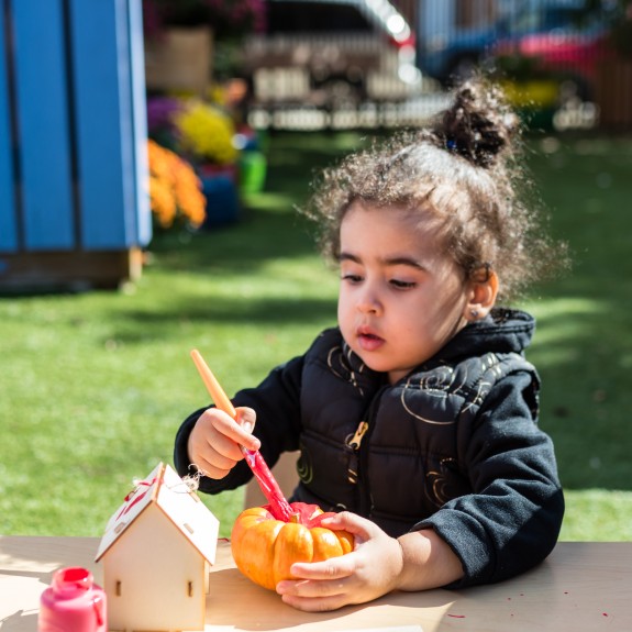 Little girl painting pumpkin