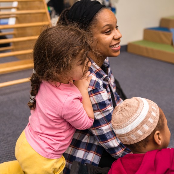 Kid leaning on mom in classroom