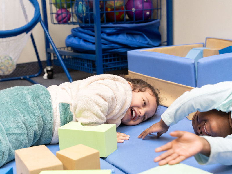 Two kids lay on mats smiling and laughing together